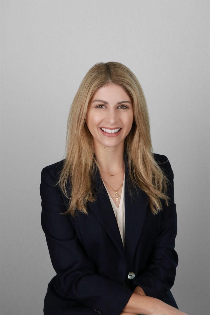 Tech and startup headshot example: a professional in a navy blazer over a white top with a warm, approachable smile on a light studio background